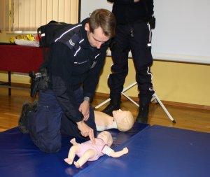 Policjant prezentuje zasady pierwszej pomocy przedmedycznej