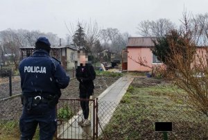 Policjant w trakcie kontroli osoby mieszkającej na terenie ogródków działkowych