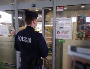 Policjant w trakcie kontroli przestrzegania obostrzeń sanitarnych w sklepie na terenie Milicza