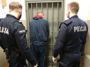 Policjanci pilnują zatrzymanego mężczyznę