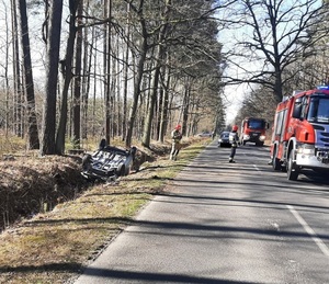 Miejsce zdarzenia drogowego, w przydrożnym rowie na dachu leży samochód