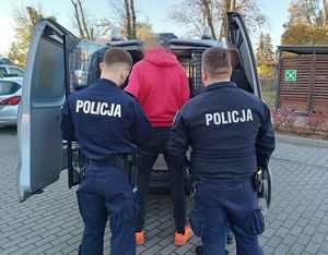 Policjanci pilnują zatrzymanego mężczyznę