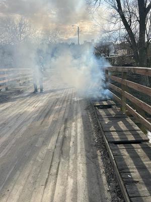 Policjant w trakcie gaszenia pożaru drewnianego mostu w miejscowości Łąki