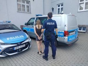 Policjant prowadzi zatrzymaną kobietę