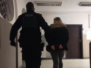 Policjant prowadzi zatrzymaną kobietę