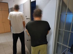 Zatrzymani mężczyźni na korytarzu policyjnego aresztu