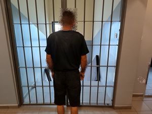 Zatrzymany mężczyzna stoi przy kracie