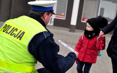 Zdjęcie poglądowe - policjant daje dziecku elementy odblaskowe
