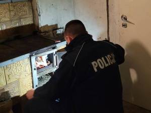 Policjant w trakcie rozpalania pieca