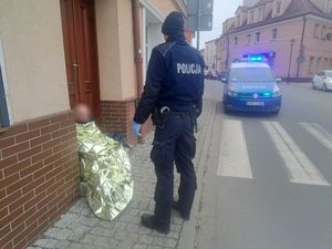 Policjant udzielający pomocy mężczyźnie siedzącemu na ziemi