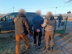 Zatrzymany mężczyzna prowadzony przez policjantów