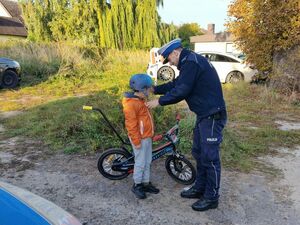 Policjant wręcza dziecku kask