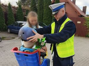 Policjant wręcza dziecku kask