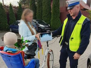 Policjant wręcza dziecku kask