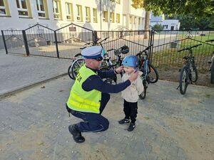 Policjant wręcza dziecku kask