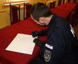 Policjant podpisuje dokument potwierdzający złożenie ślubowania