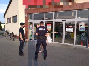 Policjanci legitymują kobietę tuż obok wejścia do sklepu