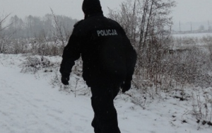 Policjant idący zaśnieżoną drogą