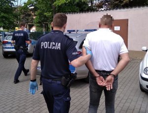 Policjant prowadzi zatrzymanego mężczyznę