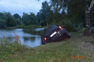 samochód osobowy marki ford częściowo zanurzony w stawie - zdjęcie od tyłu