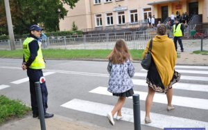 Policjant nadzoruje ruch pieszych przy szkole